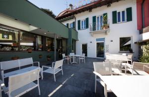 un patio al aire libre con mesas y sillas blancas en Hotel Baia di Paré en Valmadrera