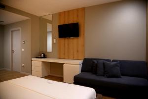 a room with a couch and a desk and a tv at Hotel One in Vlorë