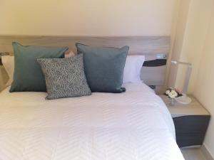 Una cama con almohadas verdes y blancas. en Apartamentos Vacacionales Joctis, 2º B en Fuengirola