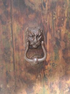 una vieja puerta de madera con una pica elefante en ella en B & B San Giovanni 9, en Gallipoli