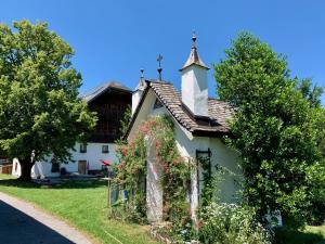 uma pequena casa branca com uma cruz no telhado em Pilznerhof em Strobl