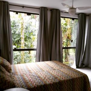 a bedroom with a bed and a large window at Suítes Km18praia in Barra do Una