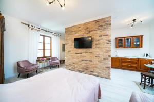 ein Schlafzimmer mit einer Ziegelwand, einem Bett und einem TV in der Unterkunft Apartamenty Magia in Lublin