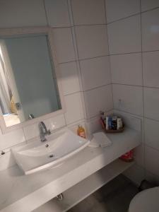y baño con lavabo blanco y espejo. en Suítes Km18praia en Barra do Una