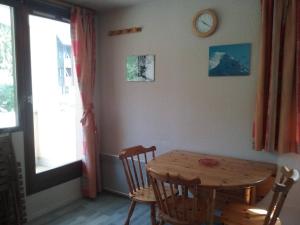 a dining room with a wooden table and chairs and a clock at Le Petit Som de Saint Pierre de Chartreuse in Saint-Pierre-de-Chartreuse