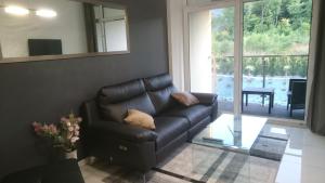 a black leather couch in a living room with a window at Apartament Dębowiec in Bielsko-Biala