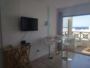 uma sala de estar com uma mesa e cadeiras e uma televisão em Apartment Portonovo Galit - Sea view - Piscina - Wifi - Old Town em Puerto del Carmen