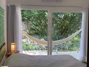 een slaapkamer met een bed en een groot raam bij Praia da Ferradurinha Guest House in Búzios