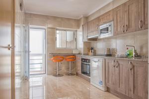 eine Küche mit Holzschränken und orangefarbenen Hockern in der Unterkunft Corbeta in Calpe