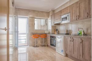 a kitchen with wooden cabinets and orange stools in it at Corbeta in Calpe