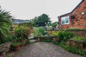 a garden in front of a house with potted plants at Featherbed Cottage in Coventry