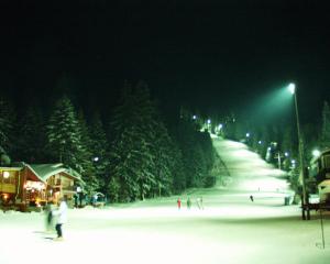 a group of people skiing down a snow covered slope at night at Iglika 2, V9 in Borovets