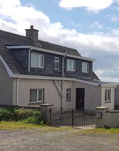 ein großes Haus mit einem Zaun davor in der Unterkunft Tornabodagh House in Ballycastle