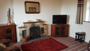 a living room with a fireplace and a television at Tornabodagh House in Ballycastle