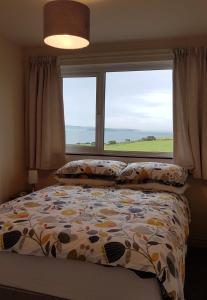 a bedroom with a bed and a large window at Tornabodagh House in Ballycastle