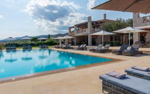 a pool at a resort with chairs and umbrellas at Therme Sea Luxury Lodge in Thermisia