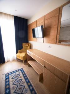 Habitación con escritorio, TV y silla. en Hotel Lahuta, en Kolgecaj