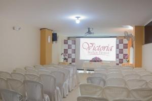 a lecture hall with white chairs and a screen at Victoria Suites Hotel in Santo Domingo de los Colorados