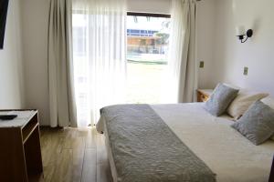 a bedroom with a bed and a large window at Apart Hotel Y Cabanas Vegasur in La Serena