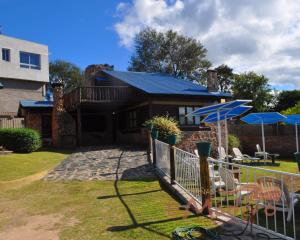 ein Haus mit einem blauen Dach mit Stühlen und Sonnenschirmen in der Unterkunft Cabañas El Madero in Villa Carlos Paz