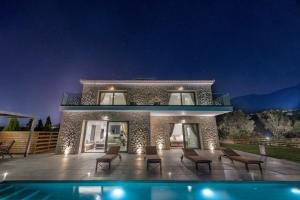 a villa with a swimming pool at night at Kefalonia Stone Villas - Villa Petros Kefalonica in Trapezaki