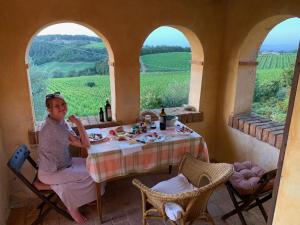 a woman sitting at a table in a room with a view at S. Bartolomeo II° - "La Loggetta" in Montepulciano