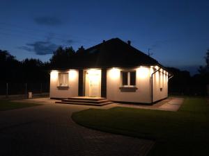 a small house lit up at night with lights at Domek pod Lasem in Ustka