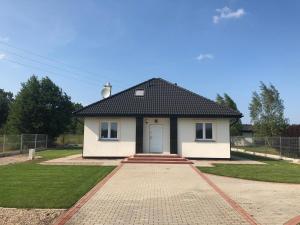 a small white house with a black roof at Domek pod Lasem in Ustka