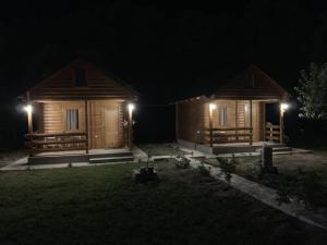twee houten huisjes 's nachts met hun lichten aan bij Little Paradise in Virpazar