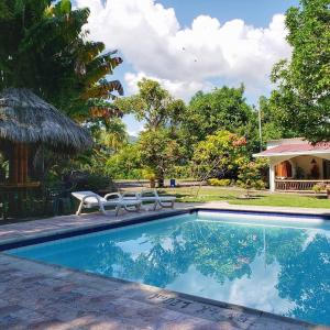 a pool with two chairs and a table and trees at Hotel Campestre El Escape in Utica
