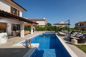 a pool with chairs and an umbrella next to a house at Villa Luka in Višnjan