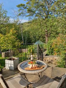 a table with a bowl of fruit and glasses of wine at Hazeldene Cottage in Holmfirth