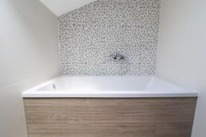 a bath tub in a bathroom with a tile wall at Brand New Apartment in Malinska in Malinska +30 photos