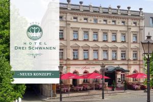 霍亨斯泰因-埃尔恩斯塔尔Hotel DREI SCHWANEN - Ristorante Due Fratelli的大楼前的红伞酒店