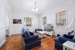 ein Wohnzimmer mit 2 blauen Sofas und einem TV in der Unterkunft Frangipani House in Toowoomba