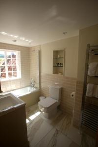 a bathroom with a toilet and a tub and a sink at Charlton End - Goodwood Events in Chichester