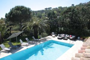 a swimming pool with chairs and a couch and trees at Villa Hortense - Golf of Saint Tropez in Sainte-Maxime