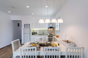 a white kitchen with a table and chairs and a counter at White Rock Milos Suites in Adamantas