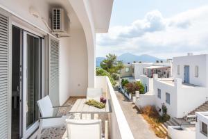 un balcón con edificios blancos, mesa y sillas en White Rock Milos Suites en Adamas