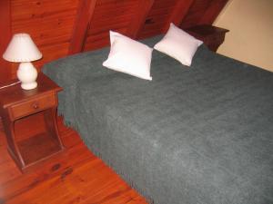 1 cama con 2 almohadas y una lámpara en una mesa en Cabañas Ayres del cerro en Merlo