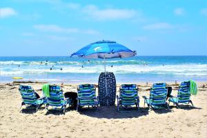 a group of chairs and an umbrella on the beach at Luv Oceanside-1 House to Beach in San Diego