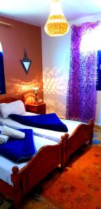 een slaapkamer met 2 bedden en een paars gordijn bij Camping & Hôtel Le Calme in Essaouira