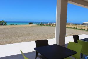 a patio with a table and chairs and a view of the beach at B&B L'EDEN DI CAPO BIANCO in Montallegro