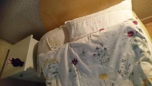 a bed with a white sheet with flowers on it at Bo i Remmarlöv in Eslöv