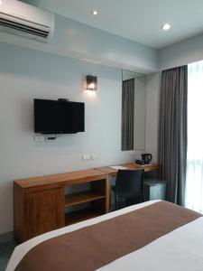 Habitación de hotel con cama, escritorio y TV. en Leez Inn Makati, en Manila