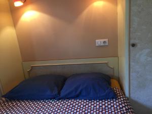 a bed with two blue pillows in a room at La Maison aux Volets Rouges in La Ferté-Beauharnais