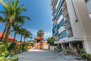 a courtyard between two buildings with palm trees at The BluEco Hotel SHA Plus in Kata Beach