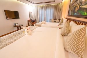 a hotel room with two beds and a television at Fivitel Hoi An Hotel in Hoi An
