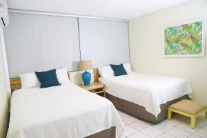 Un dormitorio con dos camas y una silla. en Buena Vida Apartments, en Rincón 7 fotos más