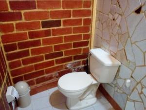 a bathroom with a toilet and a brick wall at La Posada del Cucú in Salento